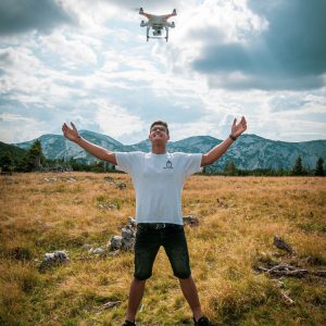 A drone flying over a man with his arms apart